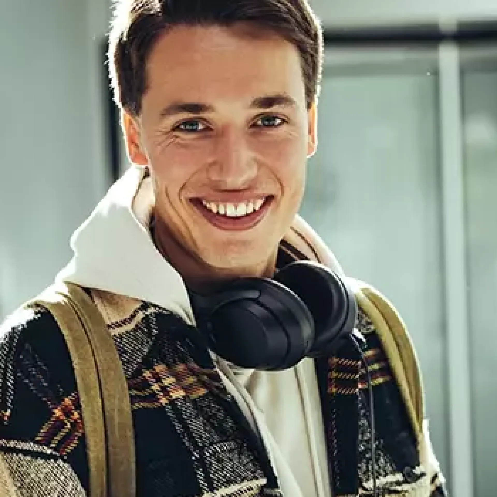 Een lachende jongeman met een koptelefoon om zijn nek.